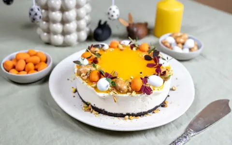 En vacker cheesecake med gul topping, dekorerad med påskägg och nötter. Perfekt för en härlig cheesecake påsk-firande.