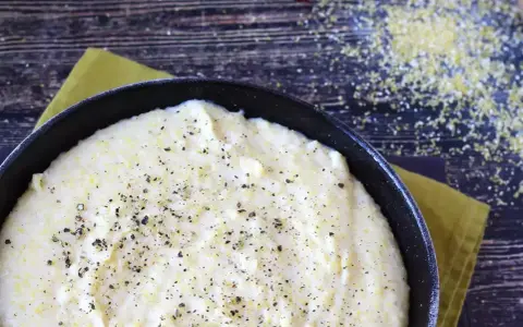 Krämig polenta i en gjutjärnspanna, strödd med peppar. Perfekt för ett enkelt polenta recept.