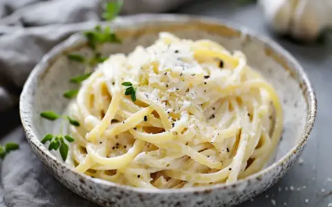 En skål med krämig ostsås pasta, toppad med riven ost och färska örter. En perfekt middag!