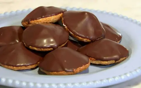 En hög med chokladöverdragna biskvier på en ljusblå tallrik. Perfekt för ett enkelt biskvier recept.