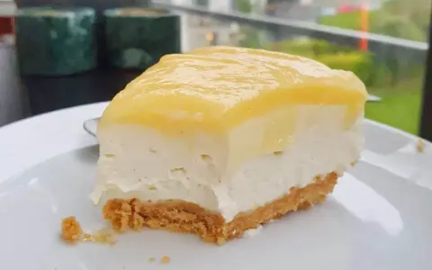 En krämig bit citron cheesecake med krispig botten, perfekt för en fika.