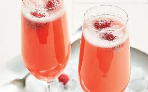 Två glas med ett rosa drink med bubbel och hallon. Perfekt för en festlig stund.