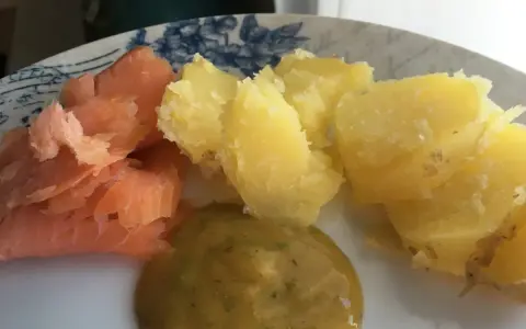 En tallrik med gravad lax, kokt potatis och en klick gravlaxsås. Perfekt för ett snabbt och gott recept.
