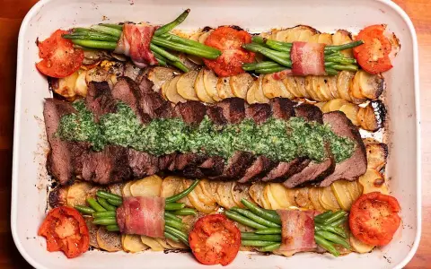 En saftig coeur de filet provencale med potatis, gröna bönor inslagna i bacon och tomater i en ugnsform.