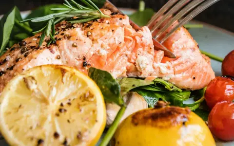 En saftig bit inkokt lax i ugn, serverad med citron, körsbärstomater och färska örter. En härlig måltid!