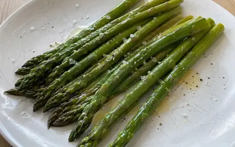 En tallrik med nykokt sparris, lätt oljad och strödd med flingsalt och peppar. Perfekt för att koka sparris till en enkel och god rätt.