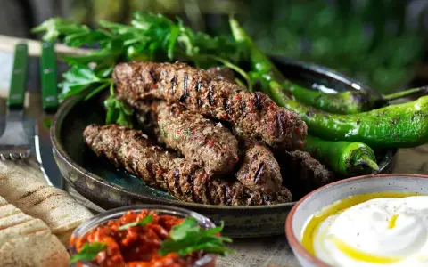 Grillade cevapcici med gröna paprikor, persilja, pitabröd och en röd röra. Ett perfekt cevapcici recept för sommaren.
