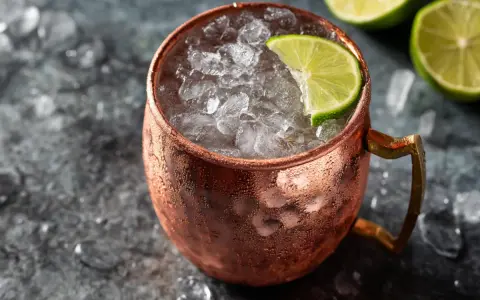 En iskall moscow mule i kopparmugg, garnerad med lime och omgiven av is.