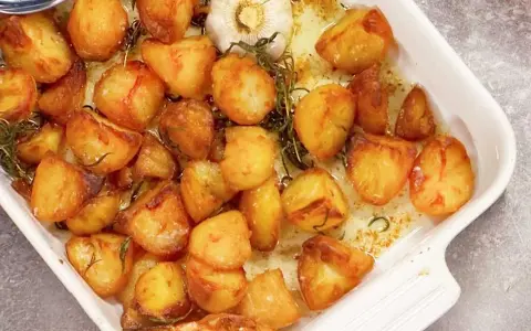 Ugnsrostad potatis med vitlök och rosmarin i en vit ugnsform. Perfekt tillbehör som doftar ljuvligt!