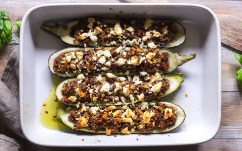 Ugnsbakade zucchinihalvor fyllda med en smakrik blandning och toppade med smulad fetaost. En härlig rätt med zucchini i ugn med fetaost.