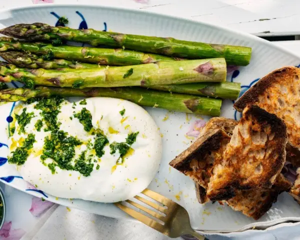 Burrata med sparris och rostat bröd, toppad med en fräsch gremolata. Perfekt för ett lätt sommarmål.