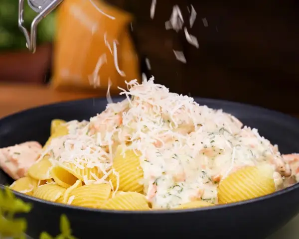 En krämig lax pasta med crème fraîche toppas med riven ost.