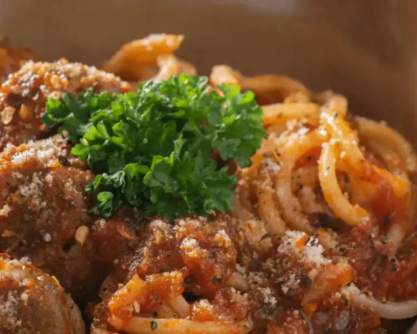 En skål med läckra polpette al sugo, köttbullar i tomatsås, serverade med pasta och toppade med färsk persilja och parmesan.