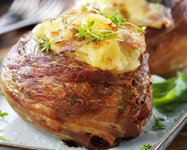 En härlig bakad potatis insvept i knaperstekt bacon, toppad med ost och örter. En riktig delikatess!