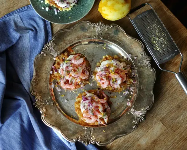 Tre potatisbullar med räkor, rödlök och dill på en silverbricka. Ett recept på potatisbullar som ser utsökt ut!