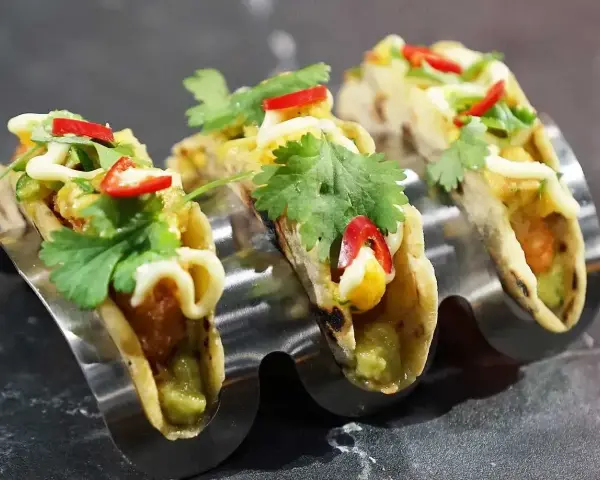 Tre läckra asiatiska tacos med koriander, chili och majs i en taco-hållare.