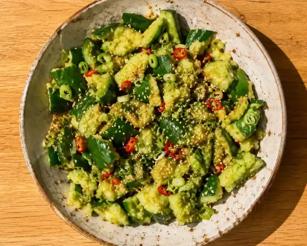 En skål med asiatisk gurksallad, toppad med sesamfrön, chili och salladslök. En fräsch och smakrik rätt.