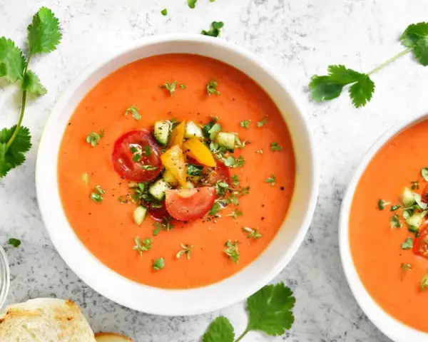 Två skålar med uppfriskande gazpacho, toppad med färska grönsaker. Ett perfekt gazpacho recept för varma dagar.