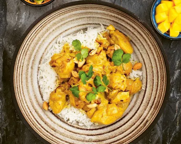 En krämig kycklingcurry med ris, toppad med koriander och jordnötter. En riktig curry nam nam!