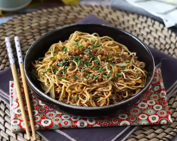 En skål med nudlar, köttfärs och grönsaker, toppad med sesamfrön och gräslök. Ett perfekt wok recept för en snabb middag.
