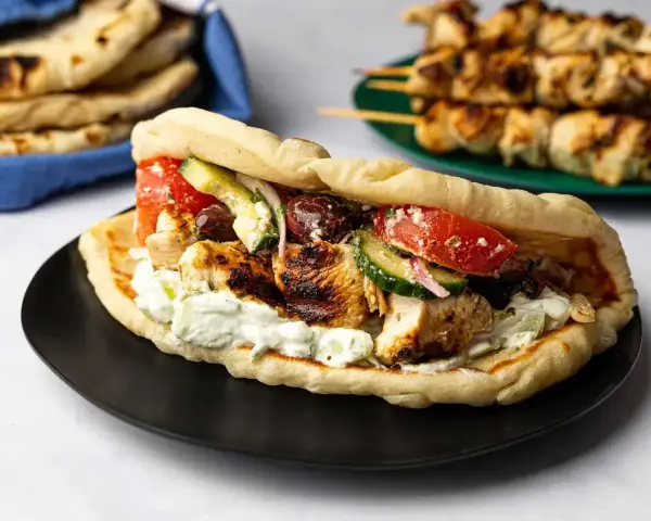 En saftig gyros med grillspett, tzatziki, tomat, gurka och oliver i pitabröd. Perfekt för ett snabbt grillspett recept.