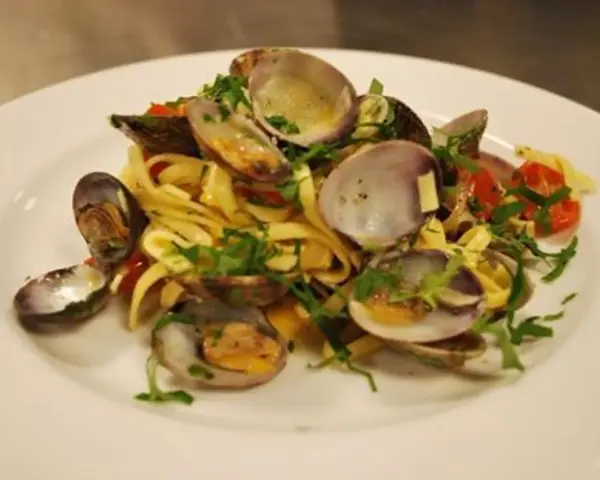 En tallrik med pasta vongole, där färska vongole-musslor blandas med tagliatelle, körsbärstomater och persilja.