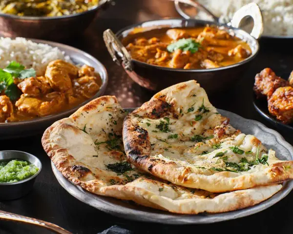 En härlig måltid med indisk mat, inklusive naanbröd, kycklingcurry och ris. Perfekt för en kväll med vin till indisk mat.