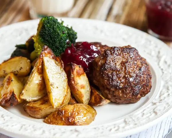 En tallrik med en saftig pannbiff, rostade potatisklyftor, broccoli och lingonsylt. Ett klassiskt pannbiff recept som passar alla.