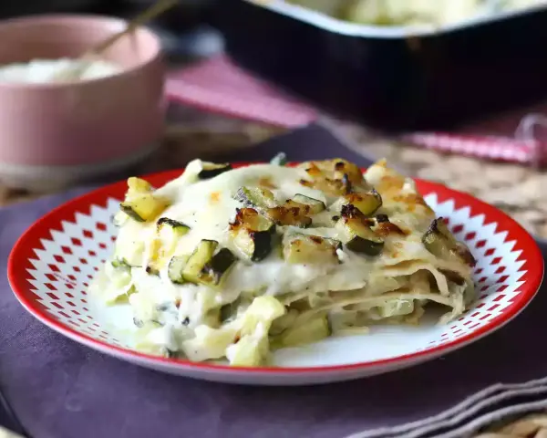 En bit krämig vegetarisk lasagne med zucchini, toppad med gyllene ost och grönsaker.