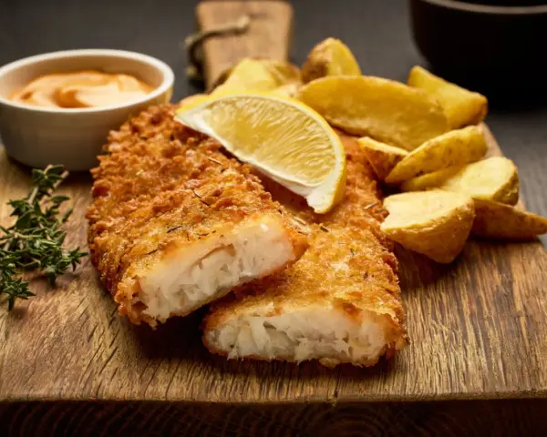 Krispigt panerad fisk med klyftpotatis och en citronskiva. Ett perfekt fisk recept för en god middag.