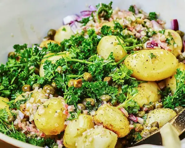 Fransk potatissallad dagen innan, med små potatisar, kapris, rödlök och persilja i en krämig dressing.