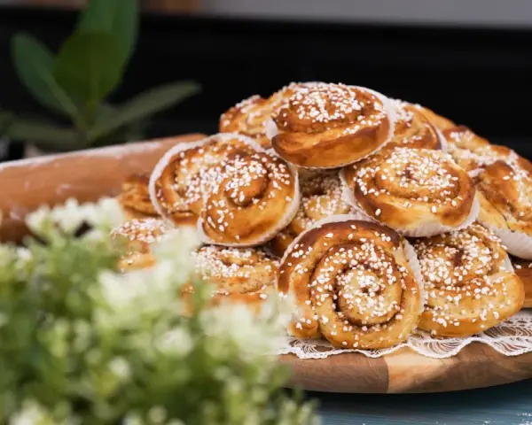 En hög med gyllene kanelbullar, redo att bakas enligt ett enkelt kanelbullar recept. En kavel ligger bredvid.