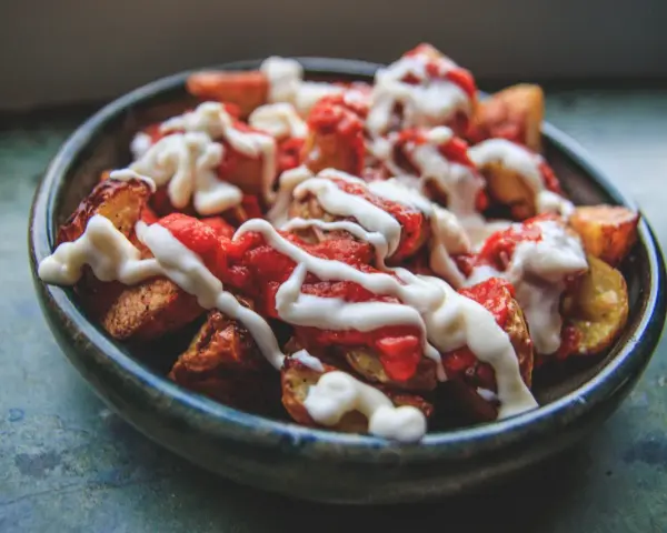 En skål med krispiga patatas bravas, toppade med en kryddig tomatsås och krämig aioli.