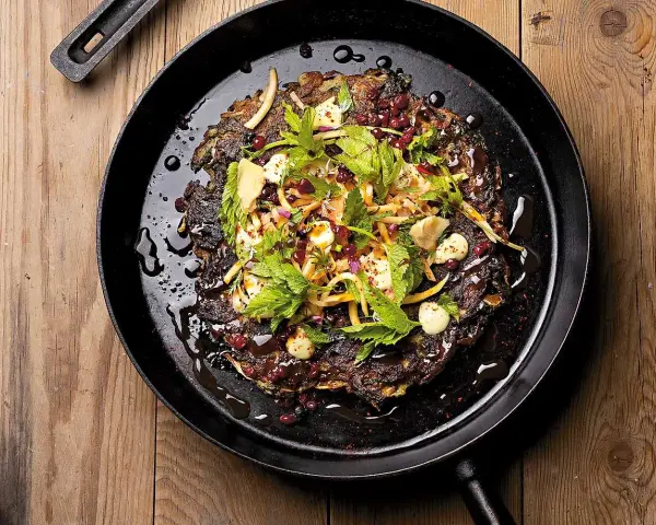 En mörk, krispig pannkaka med kirskål, toppad med färska örter, granatäppelkärnor och en krämig dressing. Ett spännande kirskål recept!