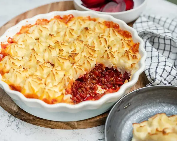En gyllene shepherd's pie med potatismoslock, fylld med en mustig lins- och rotfruktsröra. Serveras med rödbetor.
