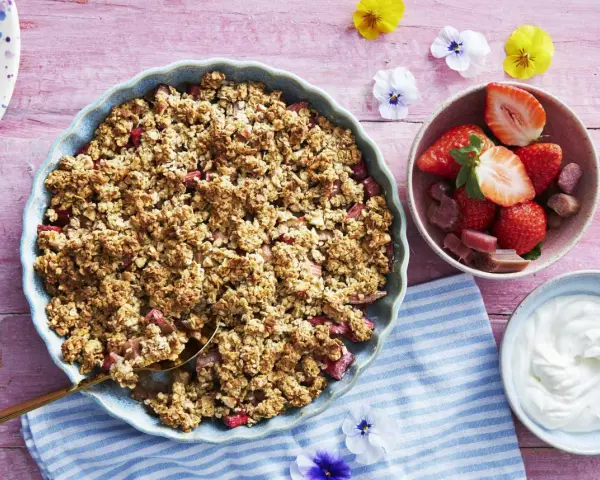 En härlig gammaldags rabarberpaj med krispigt täcke, serverad med färska jordgubbar och grädde. Perfekt sommardessert!