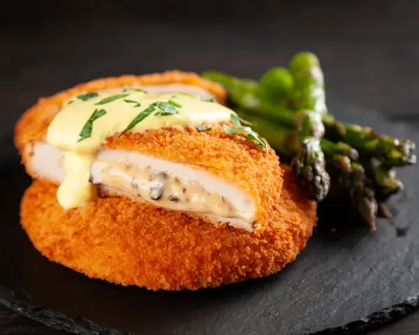 Krispig cordon bleu med krämig fyllning och hollandaisesås, serverad med sparris.