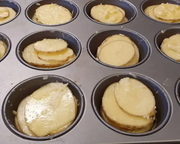 Tunna skivor av potatis i muffinsform, redo att bakas. Enkel och god rätt.