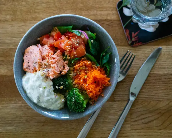 En härlig poke bowl med lax, broccoli, tomat, rivna morötter och en krämig sås. Perfekt för en hälsosam lunch.