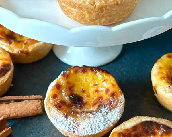 Fluffiga, gyllene pastel de nata med pudersocker och kanelstänger. En härlig fika!