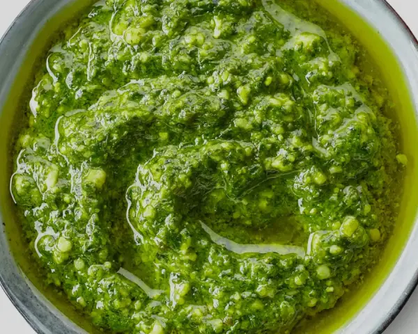 Närbild på hemmagjord pesto i en skål. Oljan flyter runt den gröna, grovhackade peston. Perfekt för att förlänga hållbarheten.
