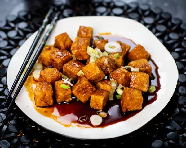 Krispiga, glaserade tofubitar med salladslök och en mörk sås. Ett läckert tofu recept som ser fantastiskt ut!