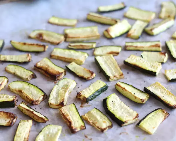 Skivor av zucchini i ugn, lätt gyllene och kryddade, redo att serveras.