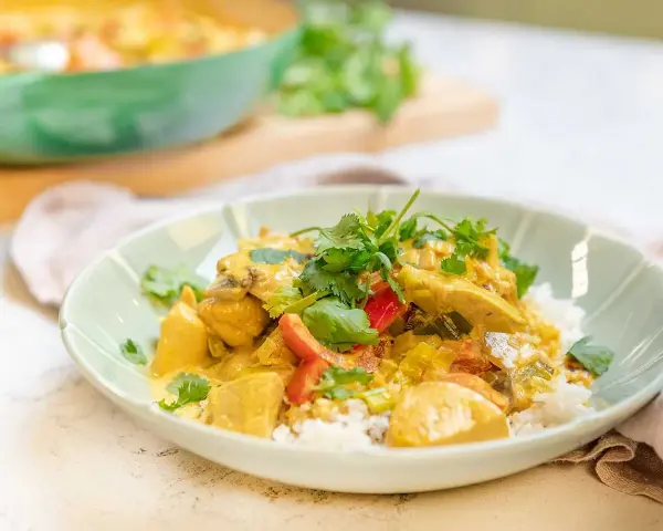 En krämig kyckling curry med ris, toppad med färsk koriander. En härlig och smakrik rätt.