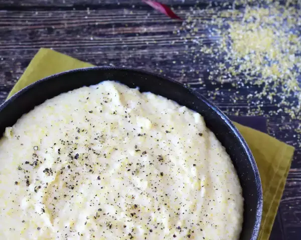 Krämig polenta i en gjutjärnspanna, strödd med peppar. Perfekt för ett enkelt polenta recept.