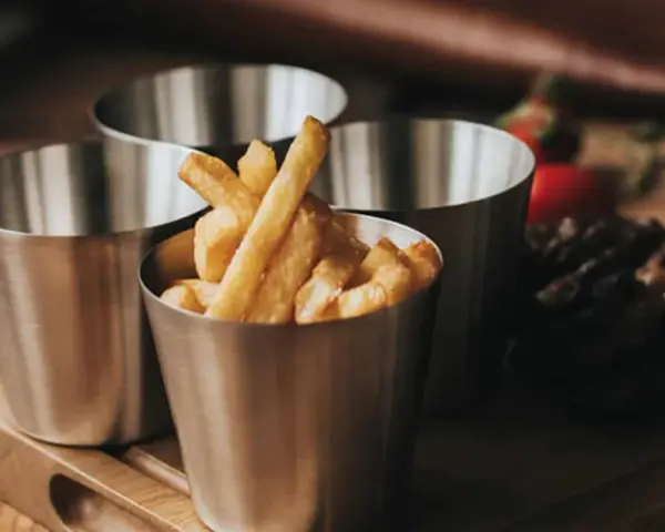 Friterade pommes i kastrull, serverade i små metallmuggar. En läcker aptitretare som påminner om hemgjord snabbmat.