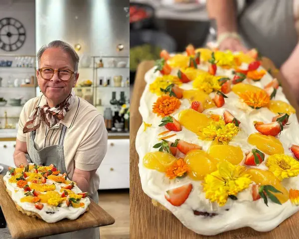 Glad kock visar upp en vacker påsktårta i långpanna, dekorerad med jordgubbar, aprikoser och gula blommor.