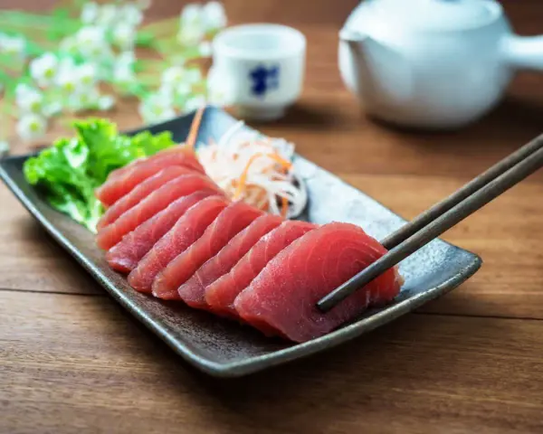Vackert upplagd tonfisk sashimi på en tallrik, redo att avnjutas med en god vin.
