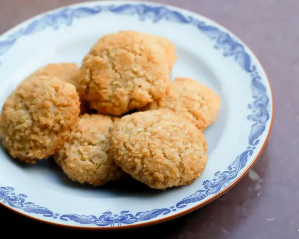 En tallrik med gyllene, glutenfria kakor med kokosflingor. Perfekt för fikat!