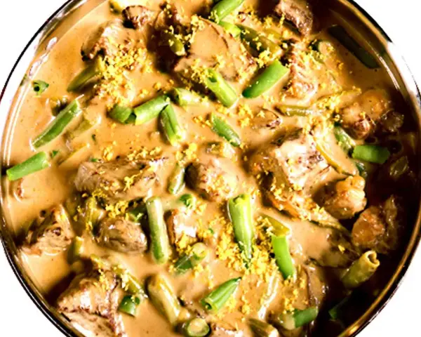 En krämig biff stroganoff med möra köttbitar och gröna bönor, toppad med gul strössel.
